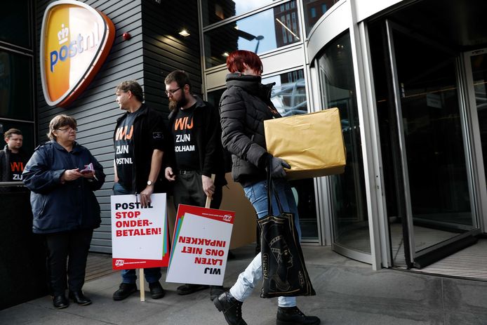 Pakketsorteerders PostNL overhandigen een gouden pakket aan de directie van PostNL. Het loodzware pakje symboliseert de zware arbeidsomstandigheden waaronder de sorteerders hun werk doen.