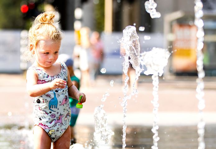 Een meisje speelt in een fontein op het Haarlemmerplein in Amsterdam.
