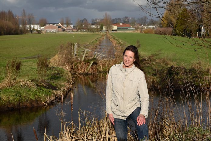 Mariette Kooijman voor het gebied waar bedrijventerrein gepland is, op de achtergrond haar ouderlijk huis.