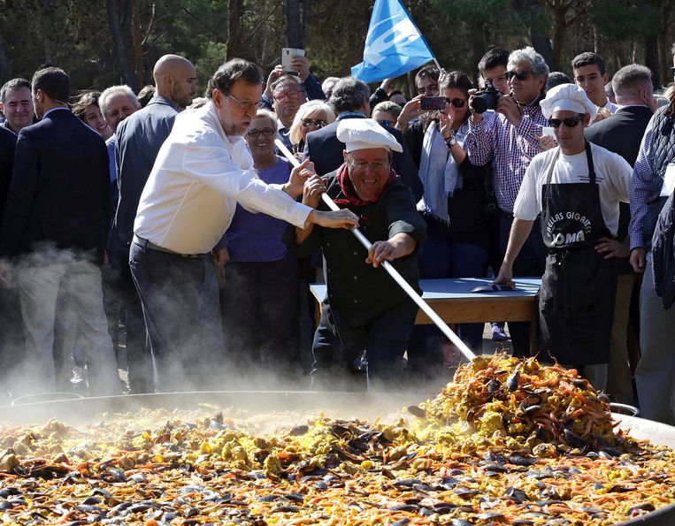 Toenmalig premier Mariano Rajoy (l) helpt in oktober 2016 bij het bereiden van paella in Zaragoza.  Beeld EPA