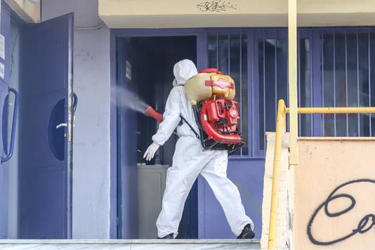 Een man desinfecteert een school in Thessaloniki waar bij een leerling het coronavirus werd vastgesteld.