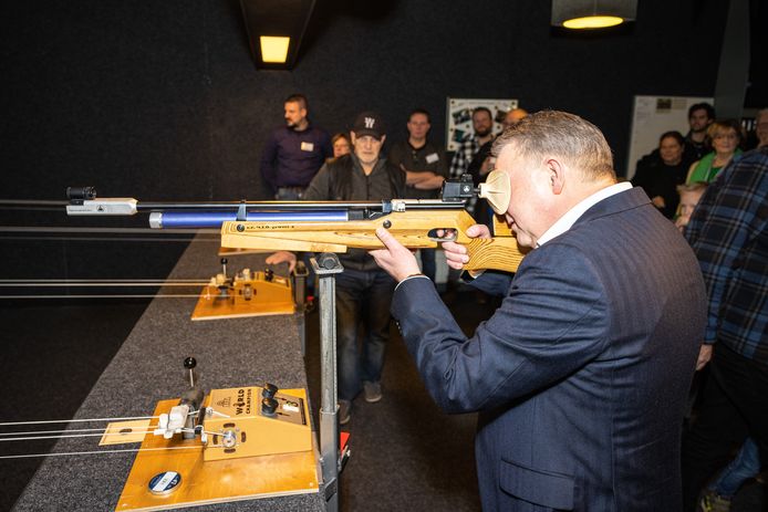Burgemeester Hans Vroomen opent het vuur op een ballon buiten beeld. Daarmee is het clubgebouw van schietsportvereniging NIO geopend.