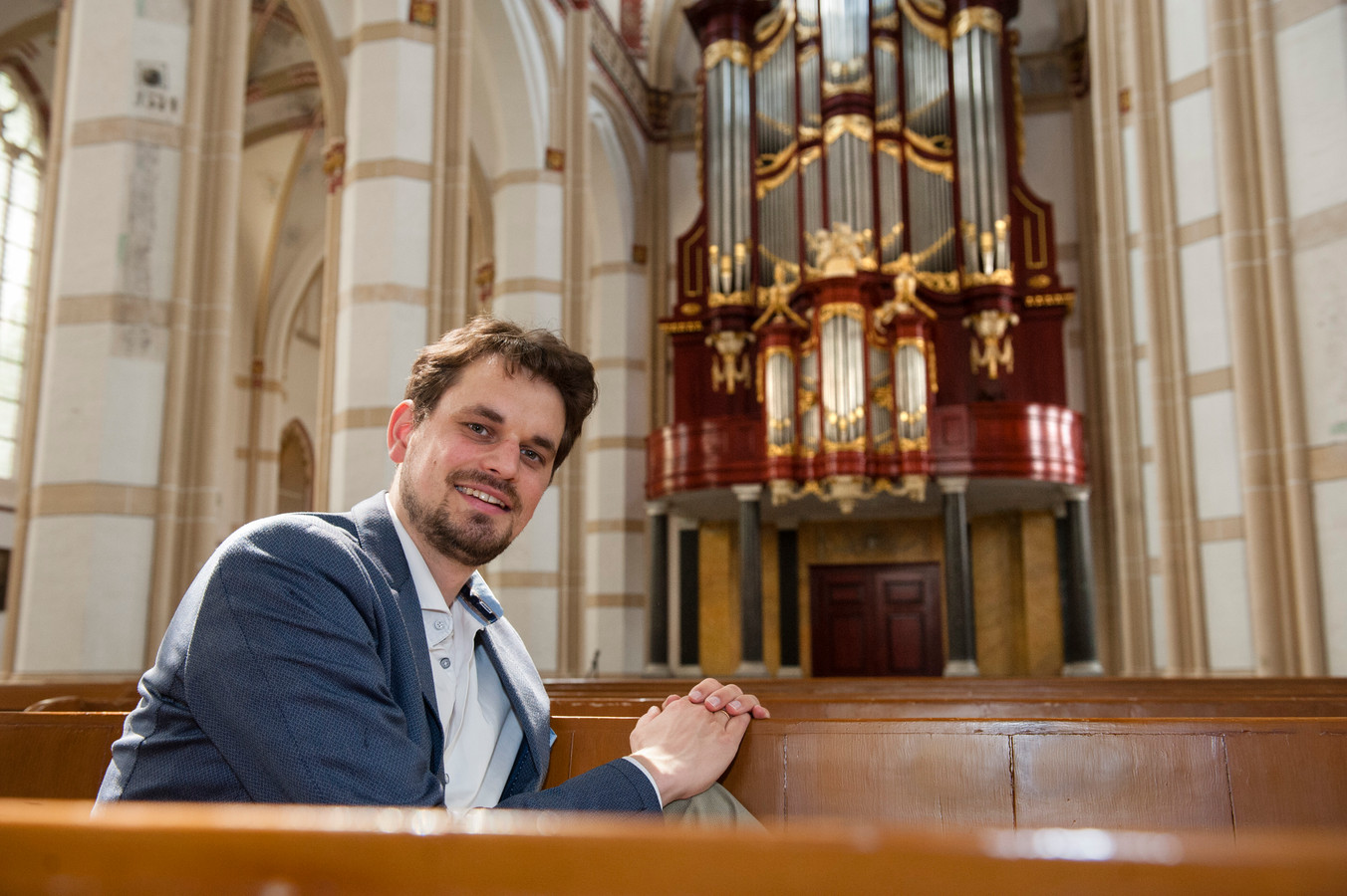 Organist Hugo Bakker met op de achtergrond het monumentale orgel van de Sint-Maartenskerk in Zaltbommel.
