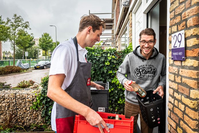 Alle Picnic-bezorgers in Alphen nemen voortaan net als Danny de lege flessen weer mee terug. Menno (r) is blij met de proef; hij hoeft nu niet in de regen naar de glasbak.