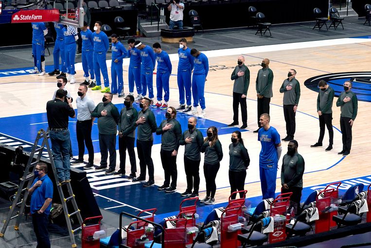 Spelers en stafleden van Dallas Mavericks luisteren naar het volkslied voor de partij tegen Atlanta Hawks, vorige week woensdag. Beeld AP