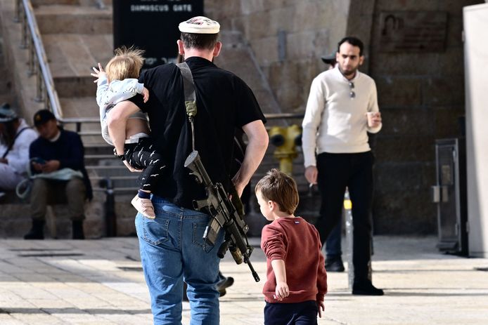 Peuter op de arm, geweer om de schouders: een Israëlische vader ziet er geen graten in.
