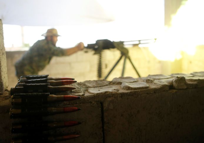 Koerdische strijder van de Volksbeschermingseenheden (YPG) vuurt met een zwaar machinegeweer naar militanten van IS in Raqqa, in juni vorig jaar.