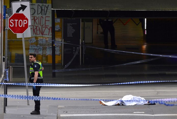 Een politieagent staat naast een bedekt lichaam in Bourke Street op de plaats van het incident.