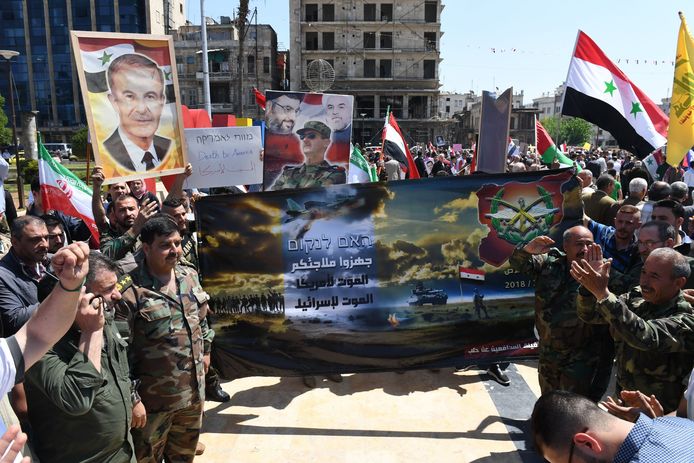 Aanhangers van het Assad-regime dragen Syrische vlaggen en portretten van hun president tijdens een betoging in Aleppo uit protest tegen de westerse aanval.