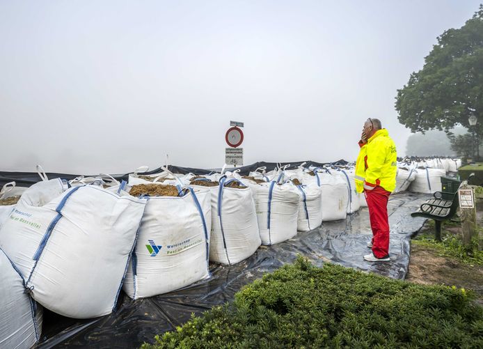 Een man van de Reddingsbrigade kijkt naar vorig jaar juli het water in de Maas in het dorpje Well. De hevige regenval en overstromingen in Noord-Limburg hebben voor veel schade gezorgd.