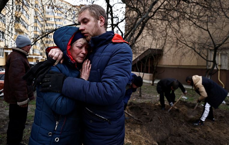 Terwijl op de achtergrond een gemeenschappelijke vriend wordt begraven, troosten Ljudmila en Sergey elkaar, in Boetsja. Beeld REUTERS