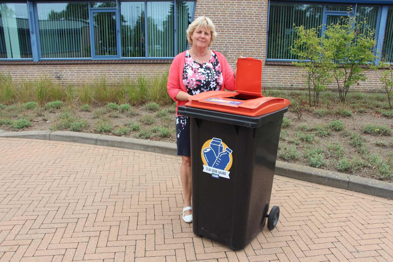 Wethouder Anjo Bosman met een variant op de pmd-container. De uitvoering met het extra klepje in het bovendeksel is voor verenigingen die meedoen om verpakkingsafval gescheiden van de rest van het afval in te zamelen.