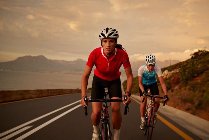Professional female cyclists on road bikes at sunset