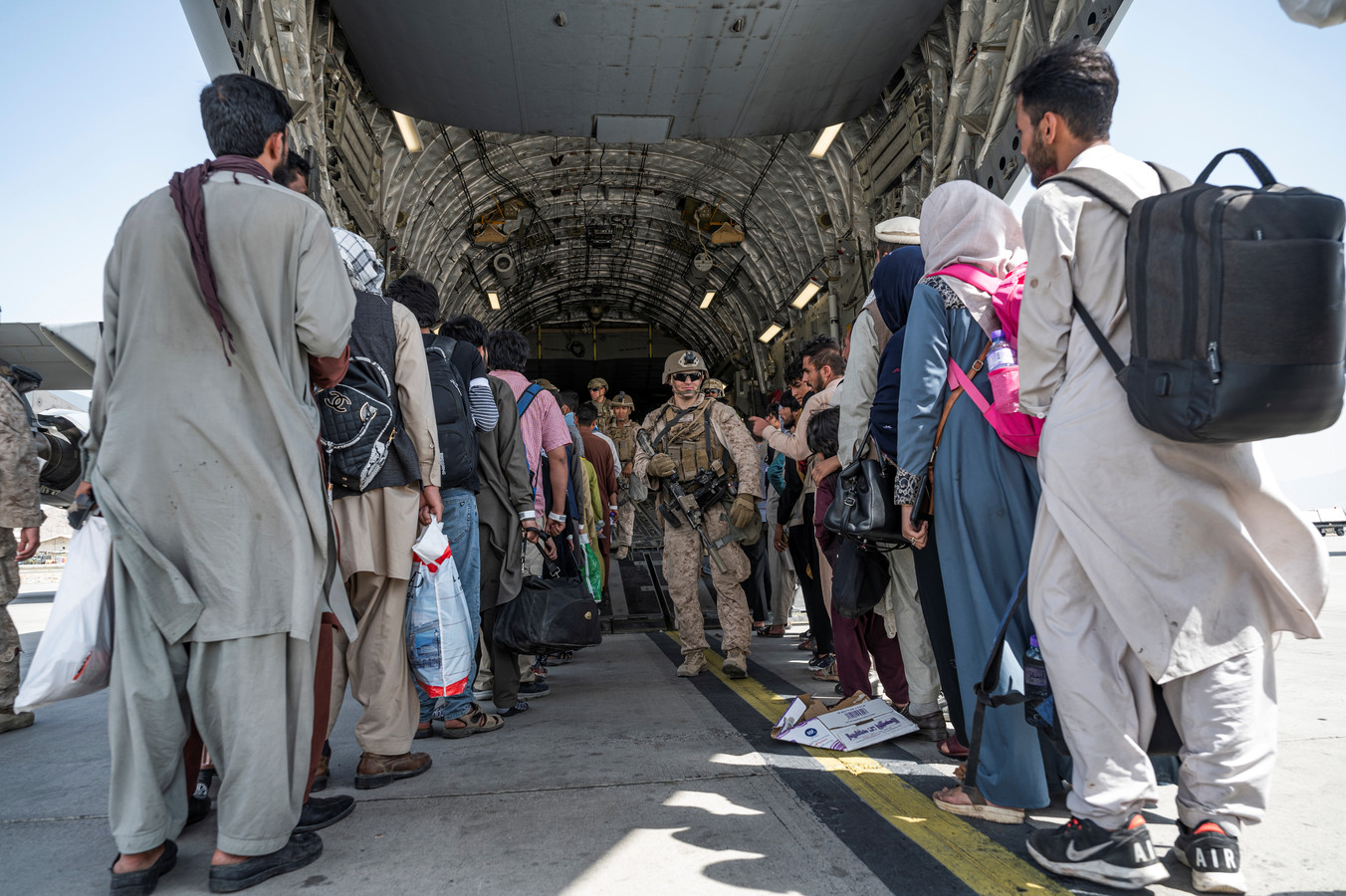 Leden van het Amerikaanse leger helpen mensen aan boord van een evacuatievliegtuig.