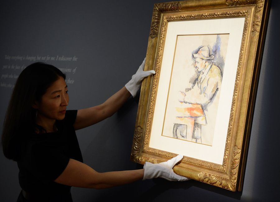 Een medewerkster van veilinghuis Christie's in New York houdt Cézannes studie voor 'De Kaartspelers' omhoog.