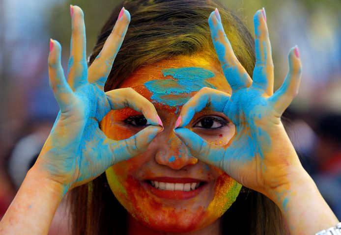 Een student van de Indiase Universiteit in Kolkata, heeft haar gezicht besmeurd met kleurrijk poeder tijdens de vieringen voor Holi. Foto Rupak De Chowdhuri