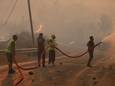 Brandweerlieden, geholpen door inwoners, blussen een brand in de Turkse kuststad Oren.