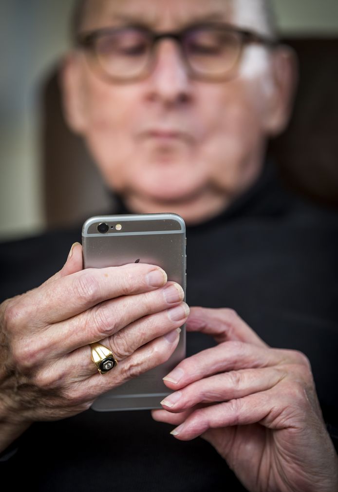 Een oudere man kijkt op zijn iPhone.