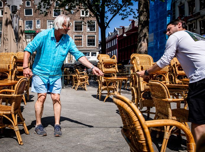 Een kroegbaas meet de afstand tussen tafels op een terras voorafgaand aan de heropening van de terrassen op 1 juni.