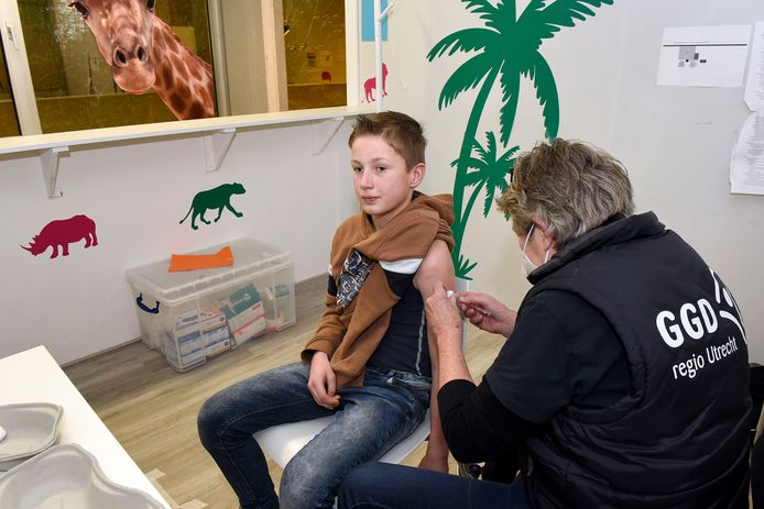 Gijs (11) krijgt zijn eerste coronavaccinatie van een GGD-medewerkster.