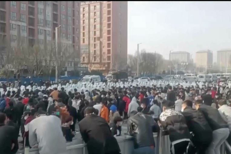 Demonstranten staan tegenover beveiligingspersoneel op het terrein van de iPhonefabriek in Zhengzhou.  Beeld AP