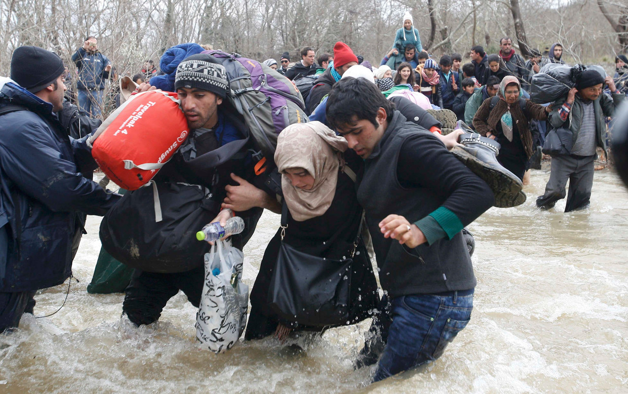 Migranten steken een rivier over vlak bij de Griekse plaats Idomeni. Beeld reuters