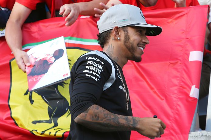 Lewis Hamilton passeert langs een spandoek van Ferrari. De zevenvoudige wereldkampioen rijdt vanaf 2025 voor de Italiaanse renstal.