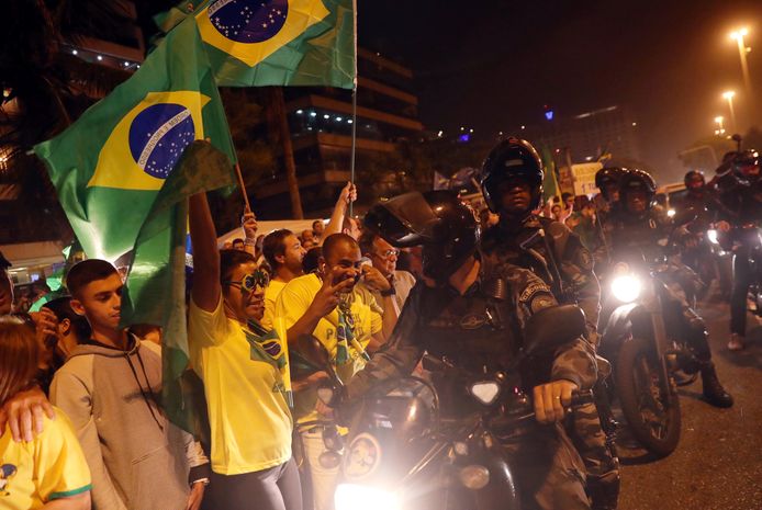 Aanhangers van de extreem-rechtse Jair Bolsonaro in Rio de Janeiro terwijl de politie aan hen voorbij trekt op de motor.