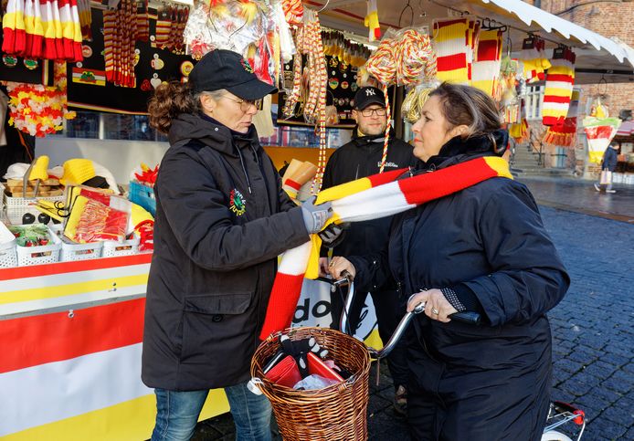 Karin de Winter (l) knoopt een klant een sjaal om voor haar Oeteldonkse kraam op de markt in Den Bosch.