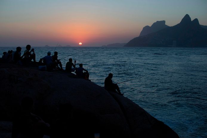 Toeristen en Braziliaanse buurtbewoners in Rio de Janeiro, genieten van de zonsondergang bij het strand van Arpoador. Foto Leo Correa