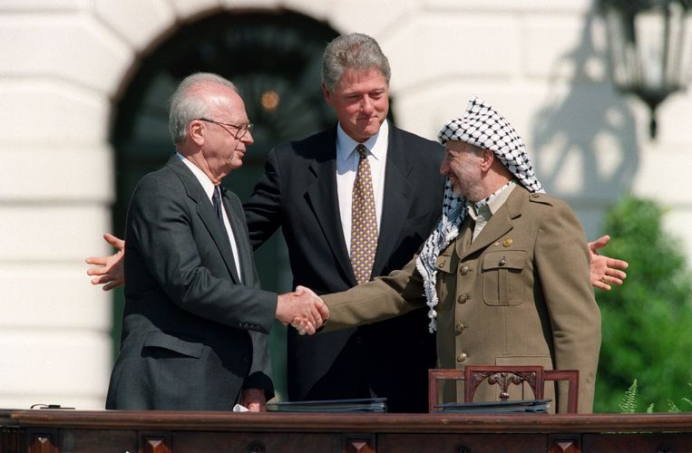 Israëlisch premier Yitzhak Rabin en Palestijns leider Yasser Arafat schudden elkaar de hand in 1993, onder goedkeurend oog van toenmalig Amerikaans president Clinton. Beeld AFP