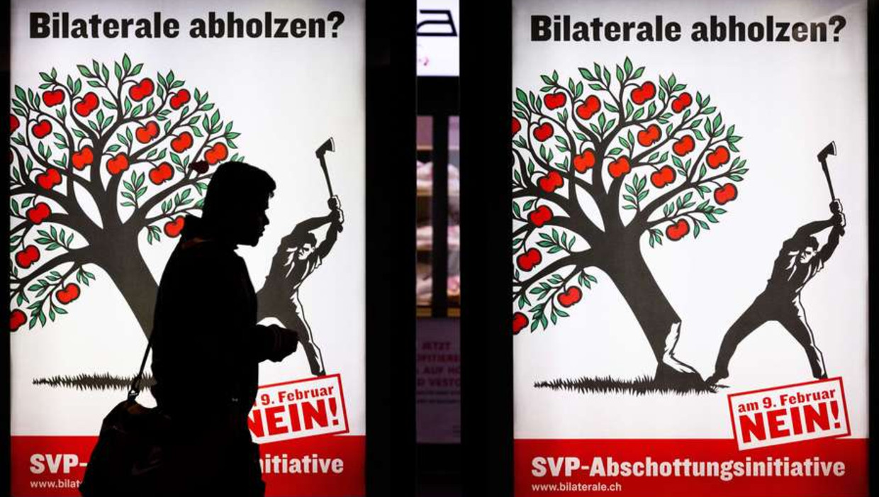 Een Zwitser loopt langs een campagneposter tegen de massa-immigratie Beeld afp