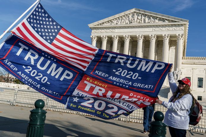 Illustratiebeeld. Een Trumpaanhanger poseert met vlaggen bij het Amerikaanse Hooggerechtshof in Washington. (11/12/2020)