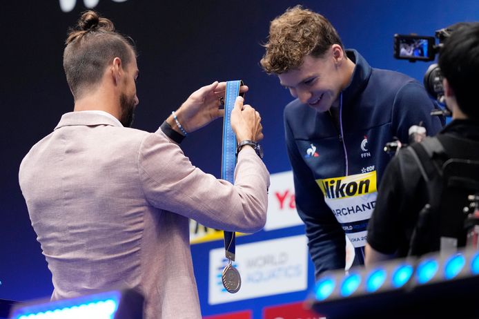 Phelps geeft Marchand z'n medaille.