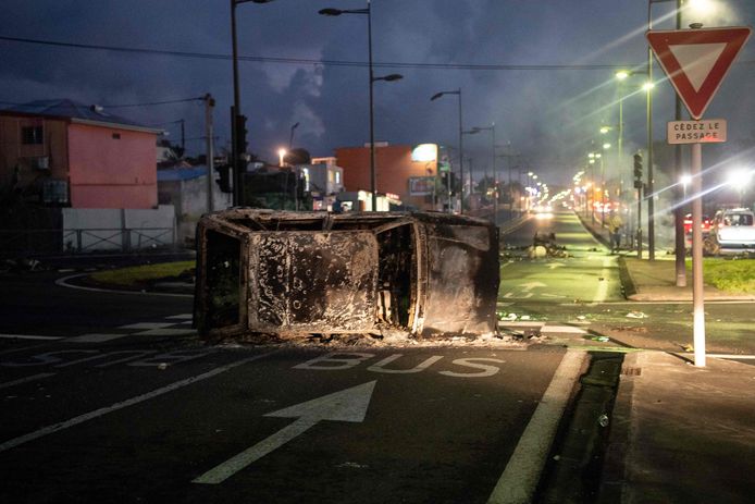 Les débris d'une voiture brûlée bloquent une route à Fort-de-France, le 23 novembre 2021, alors qu'une grève générale a été lancée le 22 novembre dans l'île de la Martinique, dans les Antilles françaises, pour réclamer la fin de la vaccination obligatoire contre le virus Covid-19 pour le personnel de santé, mais aussi des augmentations de salaire et d'autres revendications sociales.