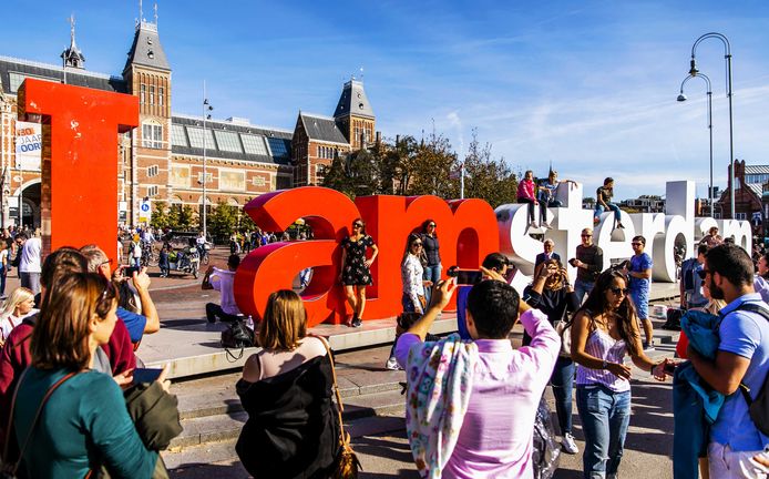 Toeristen bij de letters 'I amsterdam' op het Museumplein. De slogan in rood en wit, ruim 2 meter hoog en 23 meter breed, is bij toeristen populair als foto-object.