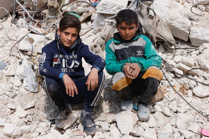 Kinderen zitten in het puin na de aardbeving in Harem, Syrië.