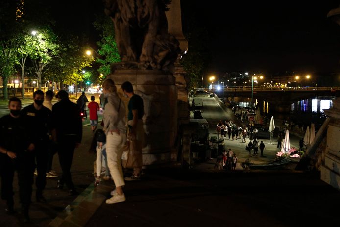 Des personnes se tiennent sur les berges de la Seine après le couvre-feu de 23 heures le 12 juin 2021, après un rassemblement aux Invalides pour une fête en plein air non autorisée.