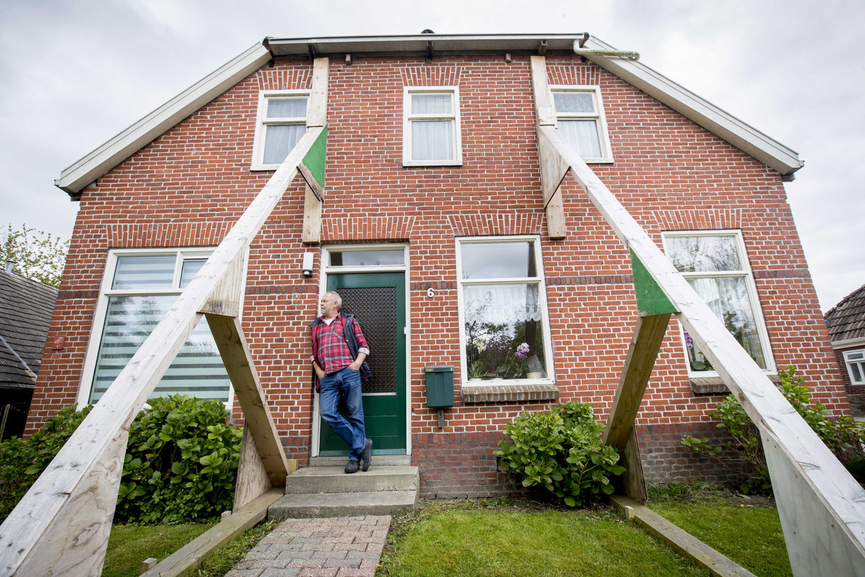 Bewoner voor zijn beschadigde woning. De woning wordt versterkt door stutten in aardbevingsgebied Loppersum.  Beeld ANP/Jerry Lampen