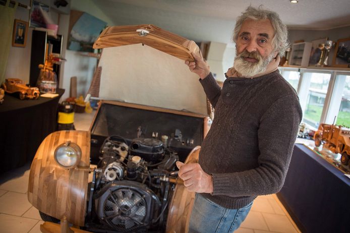De gepensioneerde meubelmaker toont trots de motor van zijn houten 2CV.