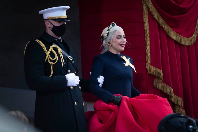 Marinier Evan Campbell begeleidt Lady Gaga van de trappen naar het podium.