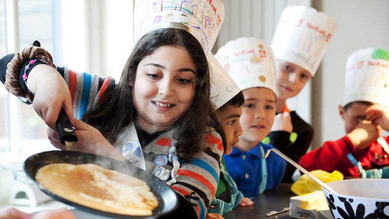 Kinderen bakken vrijwillig pannenkoeken voor ouderen. Beeld ANP