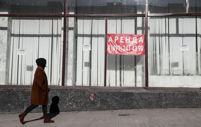Een vrouw wandelt voorbij een gesloten winkel in Moskou.