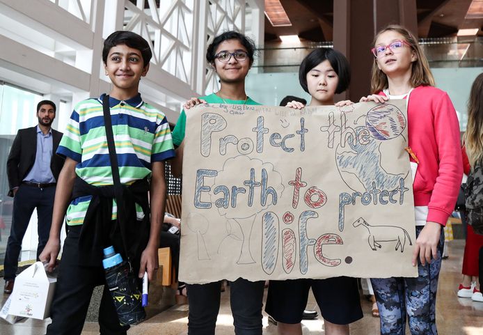 Schoolkinderen in Doha, Qatar houden een tekening omhoog met een oproep de aarde te beschermen.