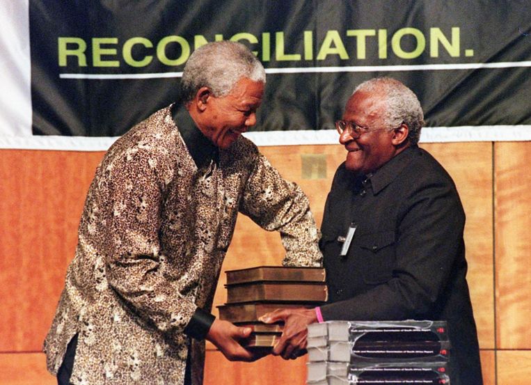 29 oktober 1998: Desmond Tutu overhandigt het vijf volumes tellende rapport van zijn Waarheidscommissie aan president Mandela. Beeld AFP