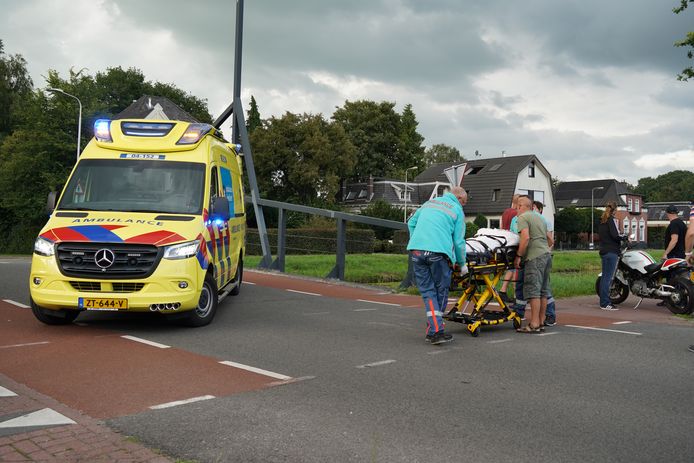 Het ambulancepersoneel is bezig om het slachtoffer de ambulance in te rijden.