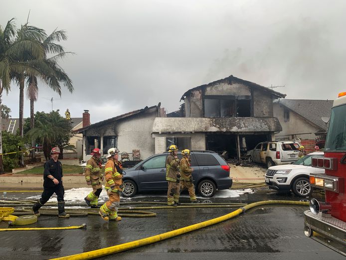 De brandweer bij een uitgebrand huis in Yorba Linda nadat het geraakt werd door een neerstortend vliegtuig.