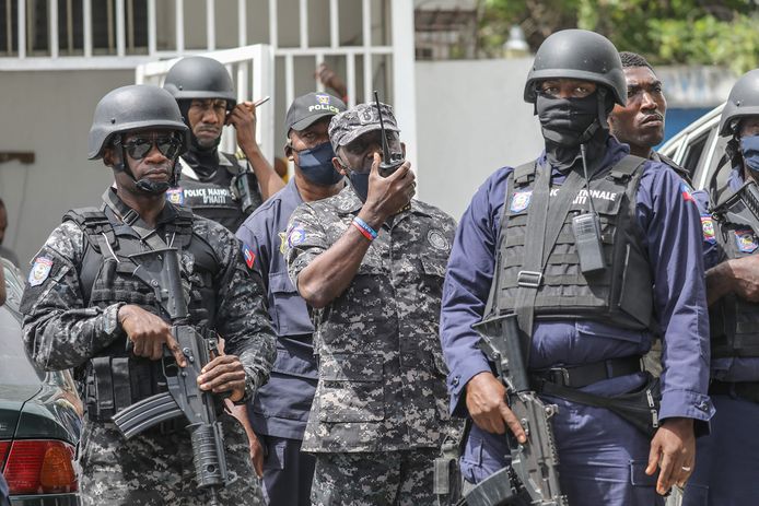 Leon Charles, het hoofd van de Haïtiaanse nationale politie (midden) geeft orders door. Hij staat met collega's aan het politiebureau waar de verdachten van de moord op de president worden vastgehouden.