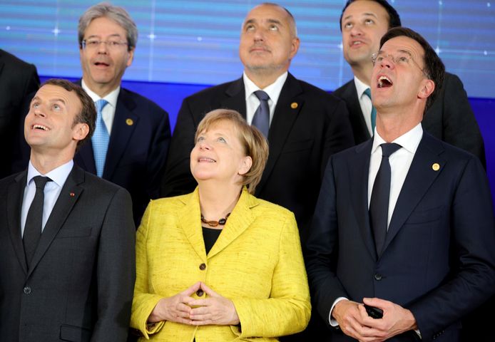 Emmanuel Macron, Angela Merkel en premier Mark Rutte kijken met open mond naar een drone.