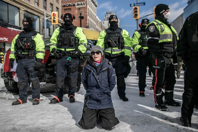 Een demonstrant knielt voor een aantal politieagenten in Ottawa kort voordat ze gearresteerd wordt.